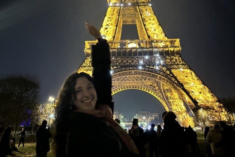 Student standing in front of Eiffel Tower at night