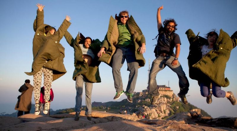 Students leaping in heavy olive green coats