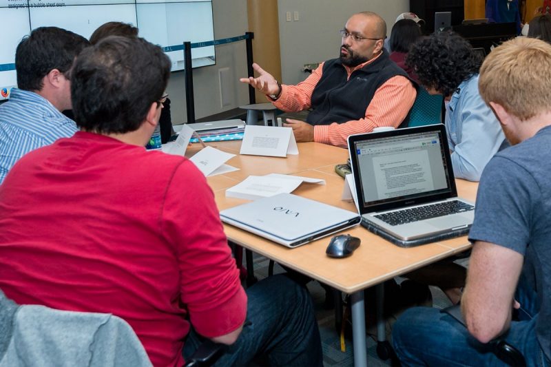 Graduate Teaching Assistants talking around a conference table.