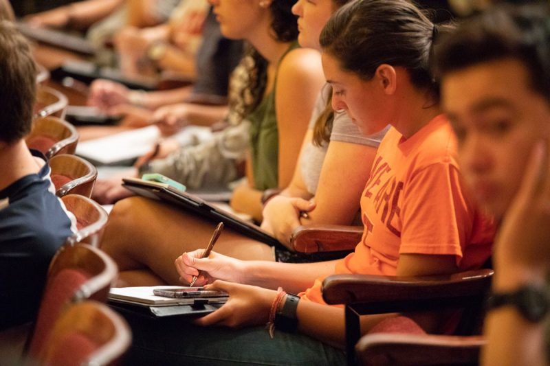 Students sitting and taking notes in a lecture hall.