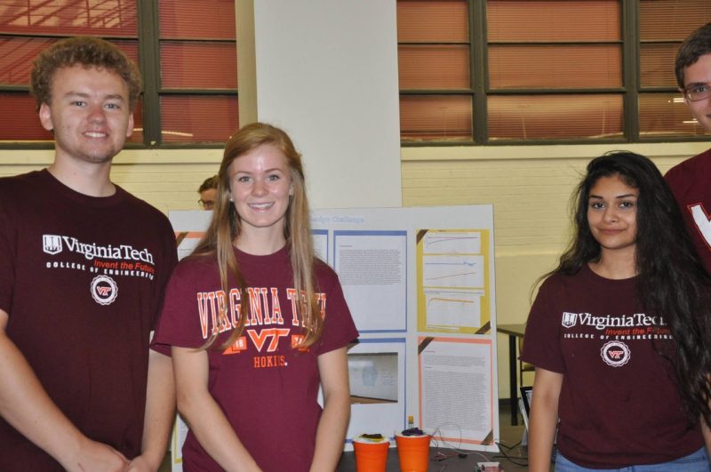 Three STEP students with their project poster in the background.