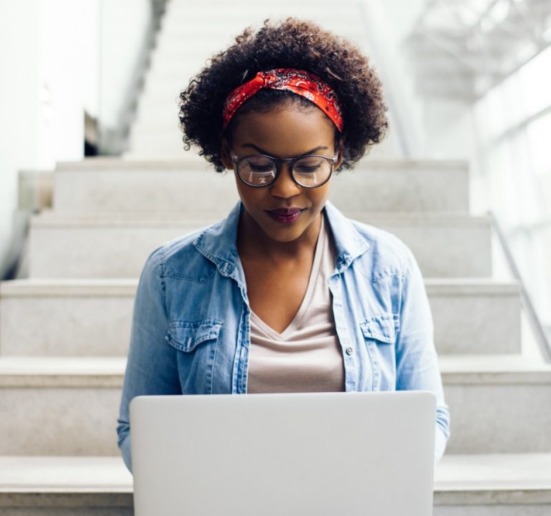 A student sitting on chairs working on a laptop