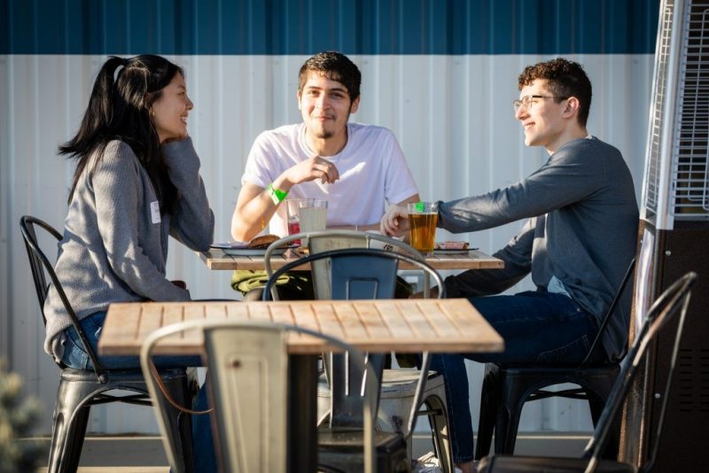 Three alumni sit around a table talking