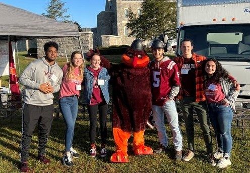 Alumni stand and smile with the HokieBird