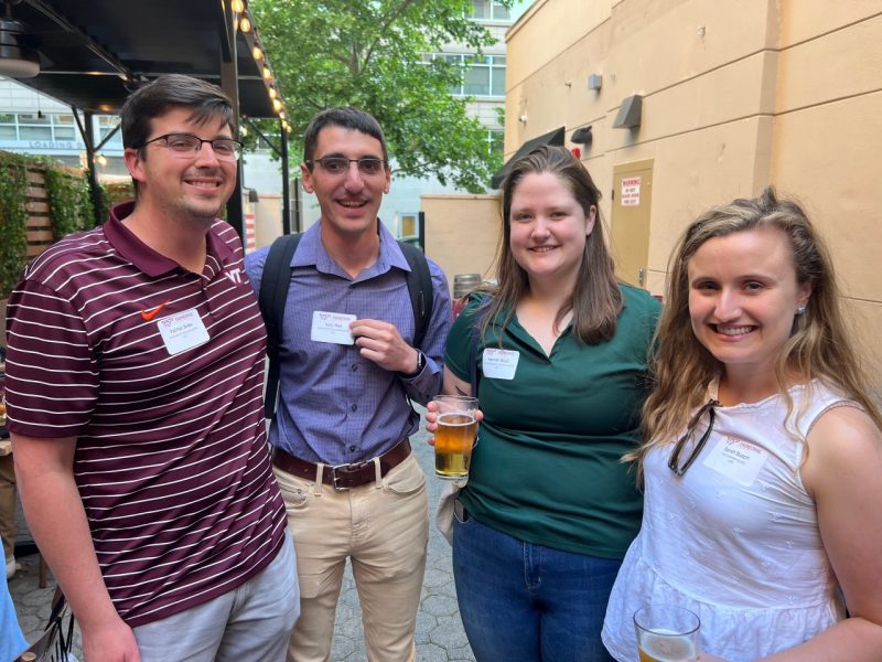 Four young alumni smile for a photo at an event