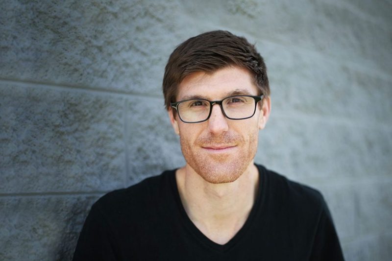 Greg Fitch poses in front of a cinderblock wall