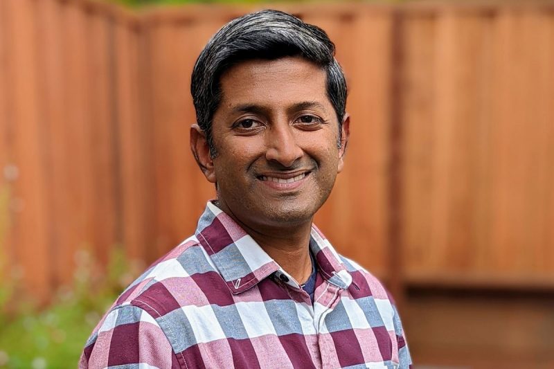 Jaishankar Sundararaman poses in front of a fence