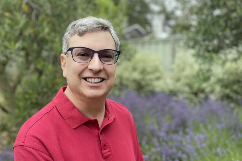 Jonathan Leblang poses in front of purple flowers