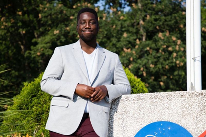 Albert Kodua, a former NASA intern at the Armstrong Flight Research Center in California, standing next to a NASA sign