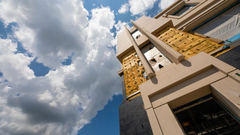 Looking up at the construction of Holden Hall with a dramatic blue cloudy sky.