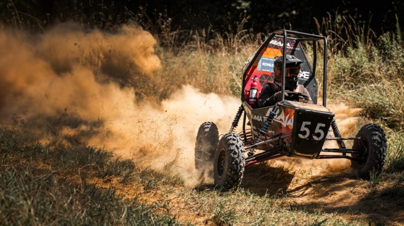 The baja car on the practice track throwing up dirt.