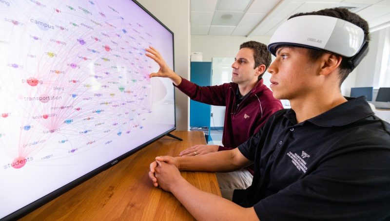 Student and faculty working on a large screen.