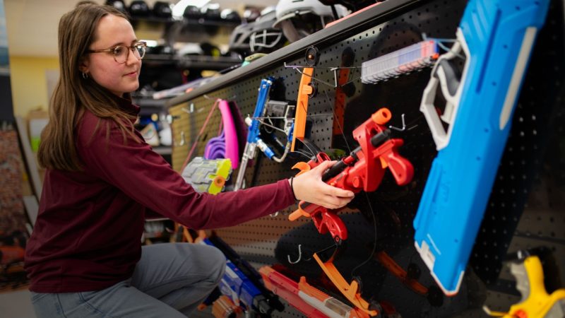 A researcher organizes NERF guns stored on a wall.
