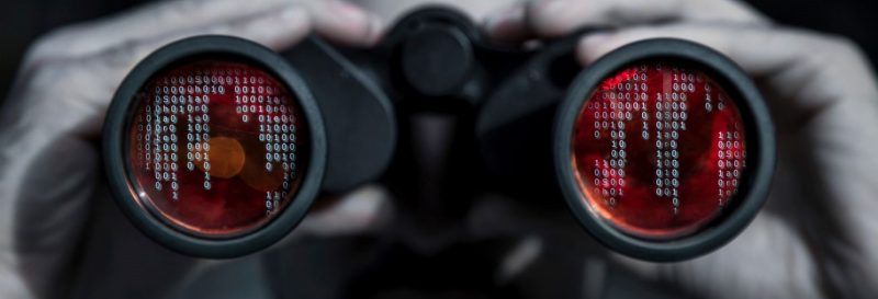 person looking through binoculars with binary code in lenses