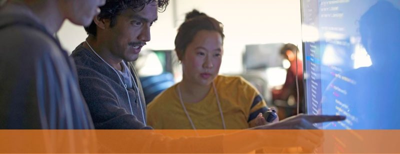 Three people reviewing code on screen