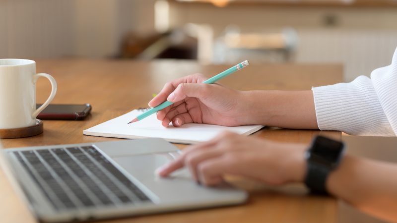 Woman taking notes and viewing computer